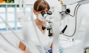 Dentystka pod mikroskopem bada, czy plomba światłoutwardzalna może wypaść. Precyzyjna praca w gabinecie.